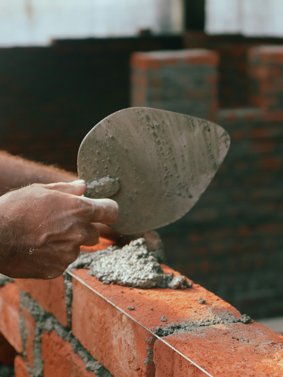 Mason laying red brick on fresh mortar with a trowel