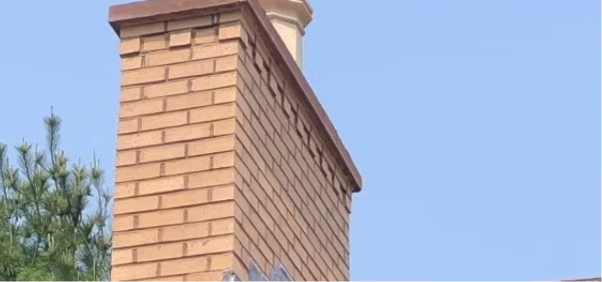 Buff brick chimney with the mortar joints washed out along one face